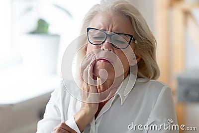 Unhealthy senior woman touch cheek suffering from toothache Stock Photo