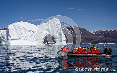 Hurtigruten`s MS Fridtjof Nansen expedition cruise ship seen through an arch in a gigantic iceberg with zodiac of intrepid touris Editorial Stock Photo