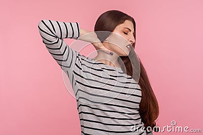 Hurting shoulders, stiff muscles. Portrait of tired sick woman in striped sweatshirt feeling unwell, massaging sore neck Stock Photo