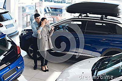 Husband Covering Wife`s Eyes Showing New Car In Auto Dealership Stock Photo