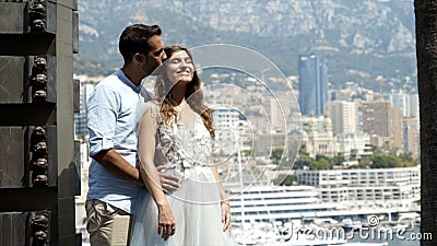 Husband embraces wife in background of city. Action. Young beautiful couple embracing on cityscape background. Newlyweds Stock Photo