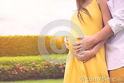 Husband embracing or hugging wife abdomen or pregnant woman with love. His wife has child or fetus inside tummy, romantic couple. Stock Photo