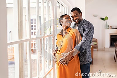 Husband embracing pregnant woman from behind Stock Photo