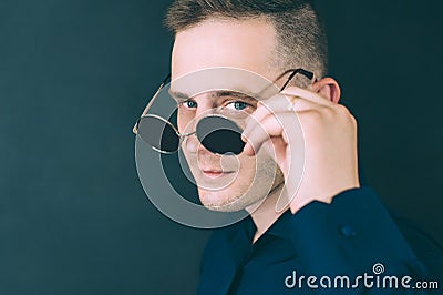Husband flirts, looks through glasses. against a dark background Stock Photo