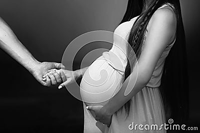 Husband holding hand of happy pregnat woman and hugging big bell Stock Photo