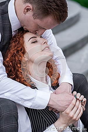 The husband kisses his wife on the forehead. A young couple. Happy redhead husband and wife. Stock Photo