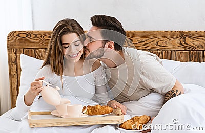 Husband kisses wife on cheek, happy wife pours coffee Stock Photo