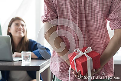 Husband making surprised wife by giving present box to her in anniversary day. Girl face in very happy expression Stock Photo