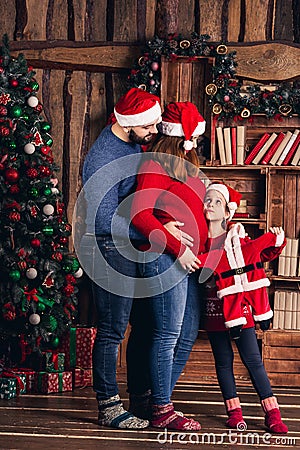 Husband, pregnant wife and daughter hold a Christmas costume for the baby. Stock Photo