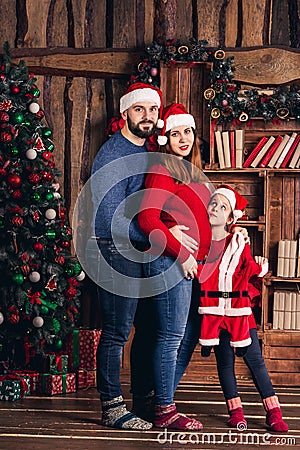 Husband, pregnant wife and daughter hold a Christmas costume for the baby. Stock Photo