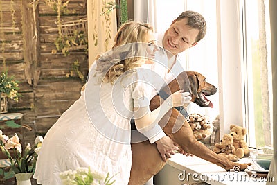 Husband, pregnant wife and a dog looking into a big window Stock Photo