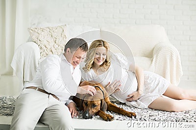 husband, pregnant wife and dog resting on the bed with the bedro Stock Photo