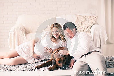 Husband, pregnant wife and dog resting on the bed with the bedro Stock Photo