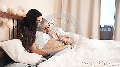 Husband stroking pregnant wife`s belly in bed Stock Photo