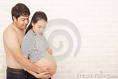 Husband and wife in pregnancy. Portrait of happy pregnant woman and husband smile. Brick background. Space for text Stock Photo