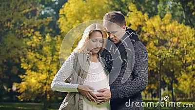 Husband and wife stroking pregnant belly, waiting for newborn baby, parenting Stock Photo