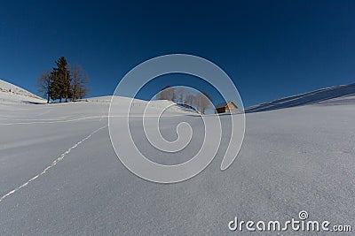 Hut with blue sky in snowy undulating winter landscape Stock Photo