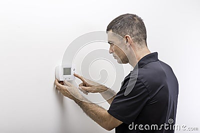 HVAC Repairman Adjusting Thermostat Stock Photo