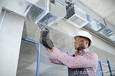 hvac african worker install ducted pipe system for ventilation and air conditioning. copy space Stock Photo