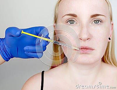 The doctor beautician conducts contour plastic lips: an injection into the lips, lip augmentation. Hyaluronic Acid Injection Stock Photo