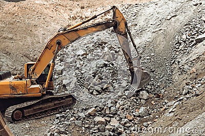 Hydraulic crusher and track type excavator backhoe machinery working. Industrial machineries working on open pit mine, ore quarry Stock Photo