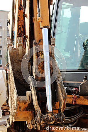 Hydraulic dirty work piston system loader, chrome plated cylinder shaft of yellow machine, construction heavy industry detail Stock Photo