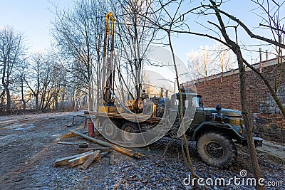 Hydraulic ground water hole drilling machine installed on the old truck with big wheels on the construction site. Groundwater well Stock Photo