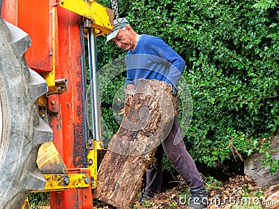 Hydraulic log splitting machine attached to a tractor the machine is being used to split large wooden logs Stock Photo