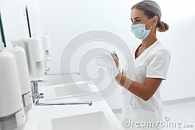 Hygiene, health care. Close up of female doctor or nurse drying hands with paper tissue at hospital. Stock Photo