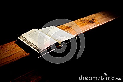 Hymnbook lies open on a church bench and is illuminate with a soft light Stock Photo