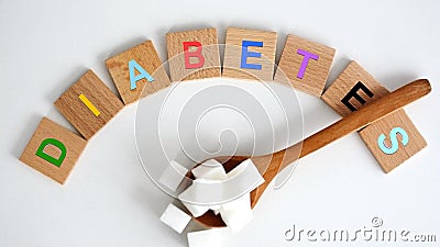 Hyperglycemia concept with white refined sugar cubes on wooden spoon and colored letters spelling the word diabetes Stock Photo