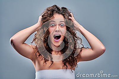 Hysterical woman expression with her hands on the head on a grey isolated background Stock Photo
