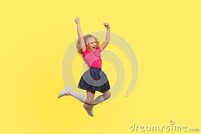 I am champion! Full length portrait of ambitious little girl in dress jumping in air and shouting from happiness Stock Photo