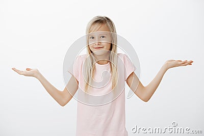 I do not know, I am kid. Portrait of unaware clueless cute girl, shrugging with spread palms, being questioned and Stock Photo