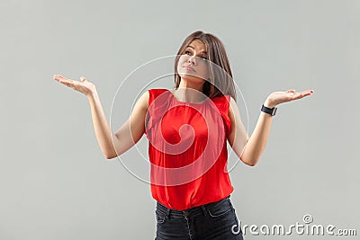 I don`t know! Portrait of puzzled beautiful brunette young woman in red shirt standing with raised arms, looking away thinking an Stock Photo