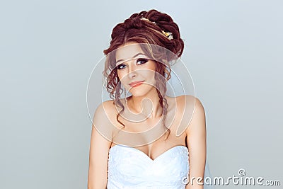 I don`t know. Studio shot of a confused young bride spouse in wedding dress gesturing with her hand on light blue white Stock Photo