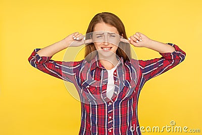 I don`t want to hear! Portrait of irritated ginger girl in checkered shirt keeping ears closed not to listen loud annoying noise Stock Photo