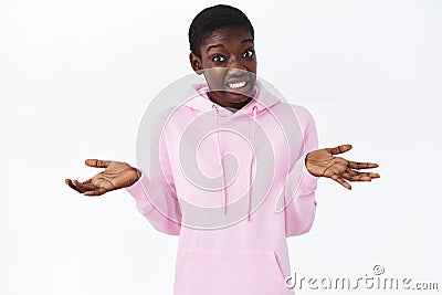I dont know. Confused african-american girl shrugging with hands spread sideways, make embarrassed awkward smile Stock Photo
