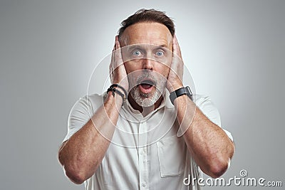 I dont wanna hear it. Studio portrait of a mature man covering his ears and looking shocked against a grey background. Stock Photo