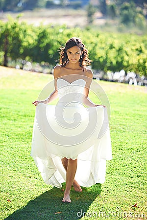 I feel like a princess. A gorgeous bride walking barefoot on grass. Stock Photo