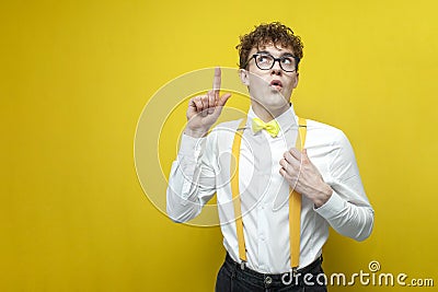 I have idea. young guy in festive outfit with glasses raises his finger up and looks up, nerd student thinks and dreams Stock Photo