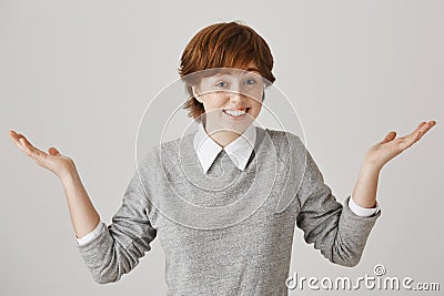 I have no clue. Portrait of carefree cute redhead female model with freckles shrugging and standing with spread hands Stock Photo