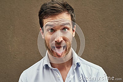 I know just how to crack you up. Portrait of a young man pulling a funny face against a dark background. Stock Photo