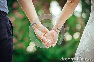 I love her tattoo on a hand. The groom holds the bride by the hand. Stock Photo