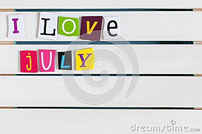 I Love July written with color magazine letter clippings on wooden board. Summer vacation concept, empty space for text Stock Photo