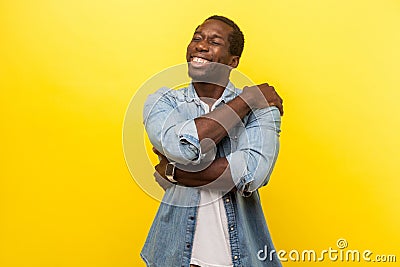 I love myself. Portrait of self-satisfied happy man cuddling himself. indoor studio shot isolated on yellow background Stock Photo