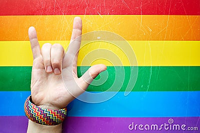 `I love you` in American sign language ASL which shows a man`s hand on the background of the flag of LGBT LGBTQ community Stock Photo