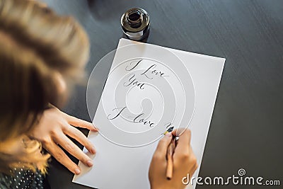 I love you. Calligrapher Young Woman writes phrase on white paper. Inscribing ornamental decorated letters. Calligraphy Stock Photo