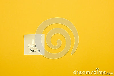 I love you and a heart handwritten on yellow note on yellow background with copy space Stock Photo