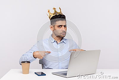 I`m big boss here! Proud authoritative businessman with crown on head sitting in office workplace, pointing himself Stock Photo